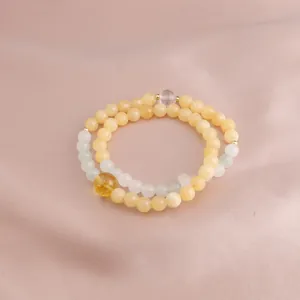 Close-up view of double-loop Golden Silk Jade and yellow crystal bracelet on pink satin fabric