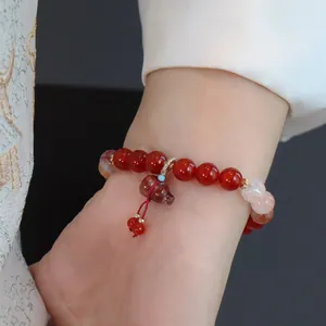 Detailaufnahme eines natürlichen roten Achat-Perlenarmbands mit geschnitztem Kürbisanhänger