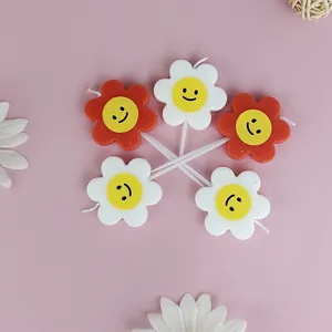 Detailed close-up of five colorful smiley flower candles for birthday cake decoration