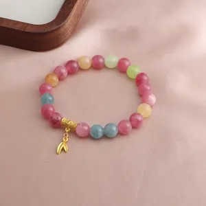 Detailaufnahme eines bunten Kristallperlenarmbands mit einem eleganten Blattanhänger aus Gold