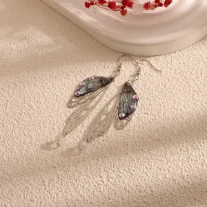 Close-up detail of ethereal blue cicada wing earrings with iridescent rhinestones.