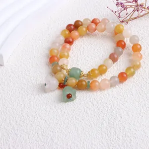 Nahaufnahme eines Jadeschmuck-Armbands mit Maiglöckchen-Anhängern in bunten Farben.