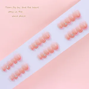 Close-up of nude pink gradient French press-on nails with sparkling rhinestones