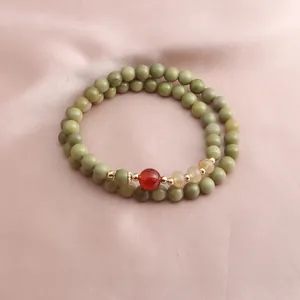 Macro detail view of the avocado green Alashan agate double-strand beaded charm bracelet.