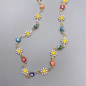 Dettaglio della collana con occhi colorati e margherite su sfondo grigio opaco