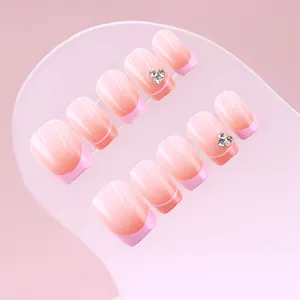 Close-up of gradient pink French press-on nails with delicate rhinestone accents
