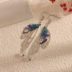 Detailed macro of iridescent butterfly wing earrings with crystals and filigree metal