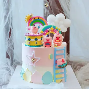 Close-up detail of cute pink pig cake toppers with rainbows and golden star decorations