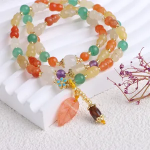 Makroansicht eines bunten Naturjade-Armbands mit Kürbisperlen und Blattanhänger
