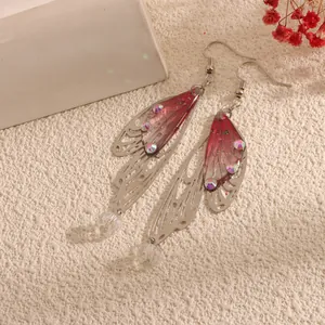Macro view of long cicada wing earrings with pink translucent film and iridescent rhinestones