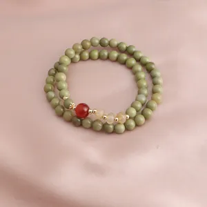 Close-up detail of double-strand bracelet with avocado green beads and red carnelian accent