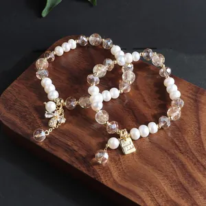 Detailansicht des 'Good Luck'-Anhängers und der Kristallbiene an Perlenarmbändern.