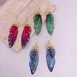 Detailed view of colorful cicada wing earrings with gold filigree and sparkling rhinestones.