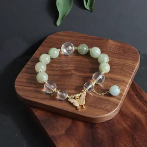 Detail eines Perlenarmbands aus Burma-Jade mit glitzerndem goldenem Schmetterlingsanhänger