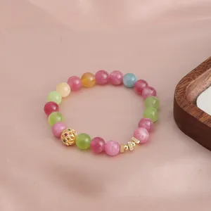 Detailaufnahme eines bunten Kristallperlenarmbands im Wassermelonen-Turmalin-Stil mit Goldanhängern.