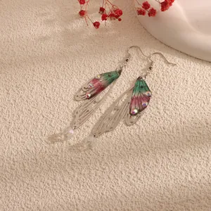 Close-up detail of long cicada wing drop earrings featuring a vibrant pink and green gradient