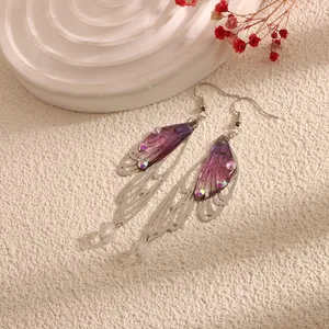 Macro detail of purple cicada wing drop earrings with silver filigree and gems