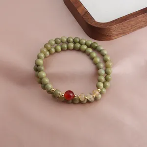 Detail view of a double-strand beaded bracelet with green avocado stone and red agate beads
