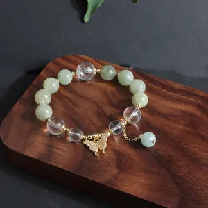 Nahaufnahme eines Armbands mit Jade- und Kristallperlen und einem goldenen Schmetterling