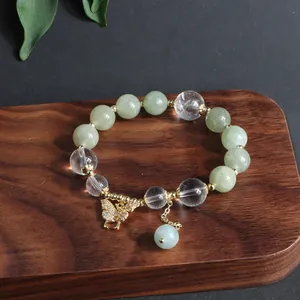 Detailaufnahme eines Jade- und Kristallperlenarmbands mit goldenem Schmetterlingsanhänger.