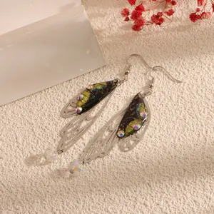 Close-up of imitation cicada wing earrings with colorful rhinestones and glass beads