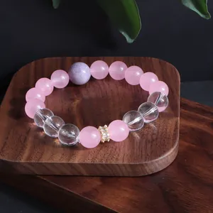 Detailaufnahme eines handgefertigten Armbands aus rosa und klarem Kristall auf Holz