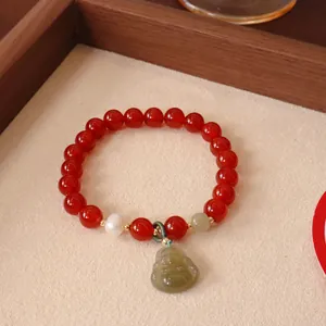 Detailaufnahme eines roten Achat-Perlenarmbands mit einem geschnitzten Buddha-Anhänger
