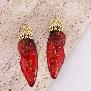 Exquisite close-up of red cicada wing earrings with gold foil and filigree detail