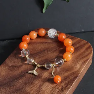 Detailansicht eines Sonnenstein-Perlenarmbands mit Bergkristallen und Fischschwanzanhänger.