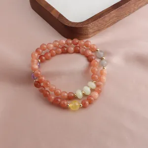 Close-up detail of a double-layered bracelet with strawberry quartz and sunstone beads