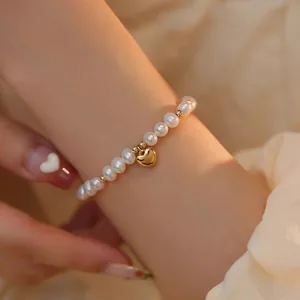 Vue rapprochée d'un élégant bracelet en perles d'eau douce avec un petit pendentif cœur doré
