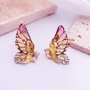 Primer plano de pendientes de alas de mariposa rosas con pan de oro y detalle cristal