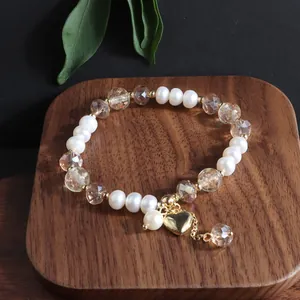 Detailansicht eines eleganten Süßwasserperlen-Armbands mit Kristallen und Goldherzanhänger