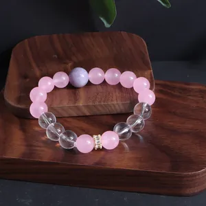 Nahaufnahme eines Armbands aus Rosenquarz und klarem Kristall auf einem Holzständer