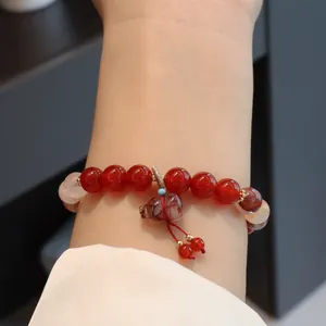 Nahaufnahme eines Armbands aus rotem Achat mit einem detaillierten Kristall-Hulu-Anhänger