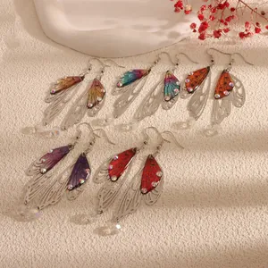 Macro detail of handmade butterfly wing earrings featuring vibrant resins and sparkling rhinestones