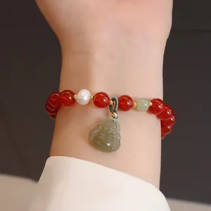Detailansicht eines handgefertigten Armbands aus rotem Achat mit einem Jade-Buddha-Anhänger