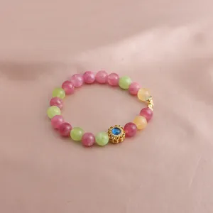 Detailansicht eines bunten Perlenarmbands mit einem goldenen Blumenanhänger
