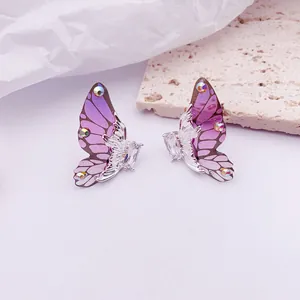 Vista macro detallada de pendientes de ala de mariposa morada con detalles de cristal
