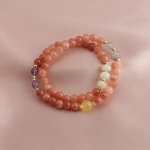 Detail view of a double-strand bracelet with strawberry quartz and amethyst beads on silk.
