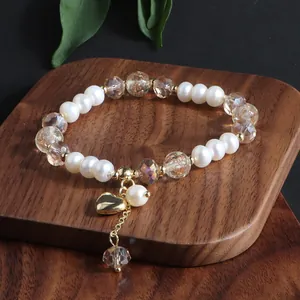 Elegante Detailansicht eines Armbands aus Süßwasserperlen und Kristall mit Herzanhänger.