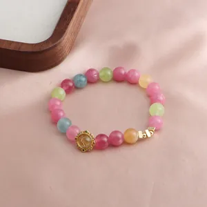 Nahaufnahme eines bunten Kristallperlenarmbands mit goldenem Lotus-Anhänger