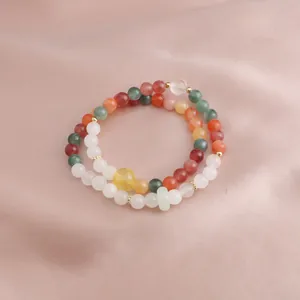 Detail of multi-colored natural stone bead bracelets on a smooth pink silk background
