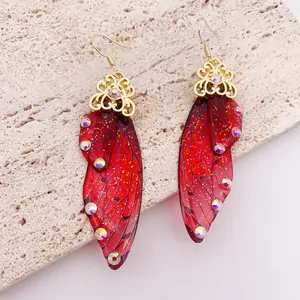 Macro detail of red translucent butterfly wing earrings with glitter and rhinestones