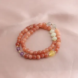 Close-up of double-loop bracelet with strawberry crystal, sunstone, and amethyst beads.