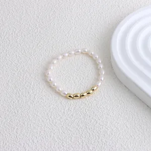 Close-up of elegant freshwater pearl bracelet with five polished gold beads on white surface.