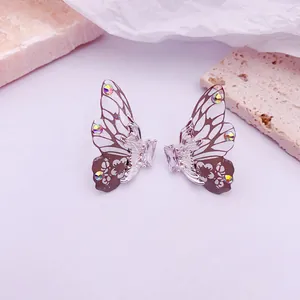 Primer plano de pendientes de alas de mariposa en degradado con cristales brillantes.