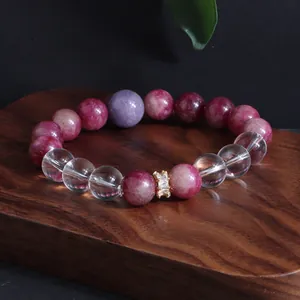 Makroansicht eines Kristallperlenarmbands mit rosa und lila Perlen auf Holzständer