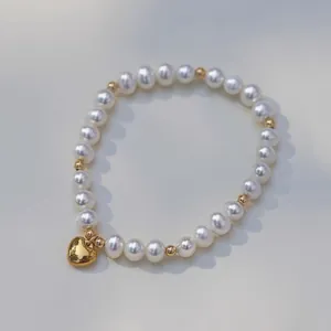 Vue détaillée d'un élégant bracelet en perles d'eau douce avec un pendentif cœur doré poli.