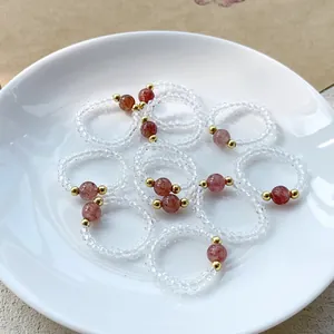 Nahaufnahme von elastischen Perlenringen mit Erdbeerkristall und facettiertem Glas